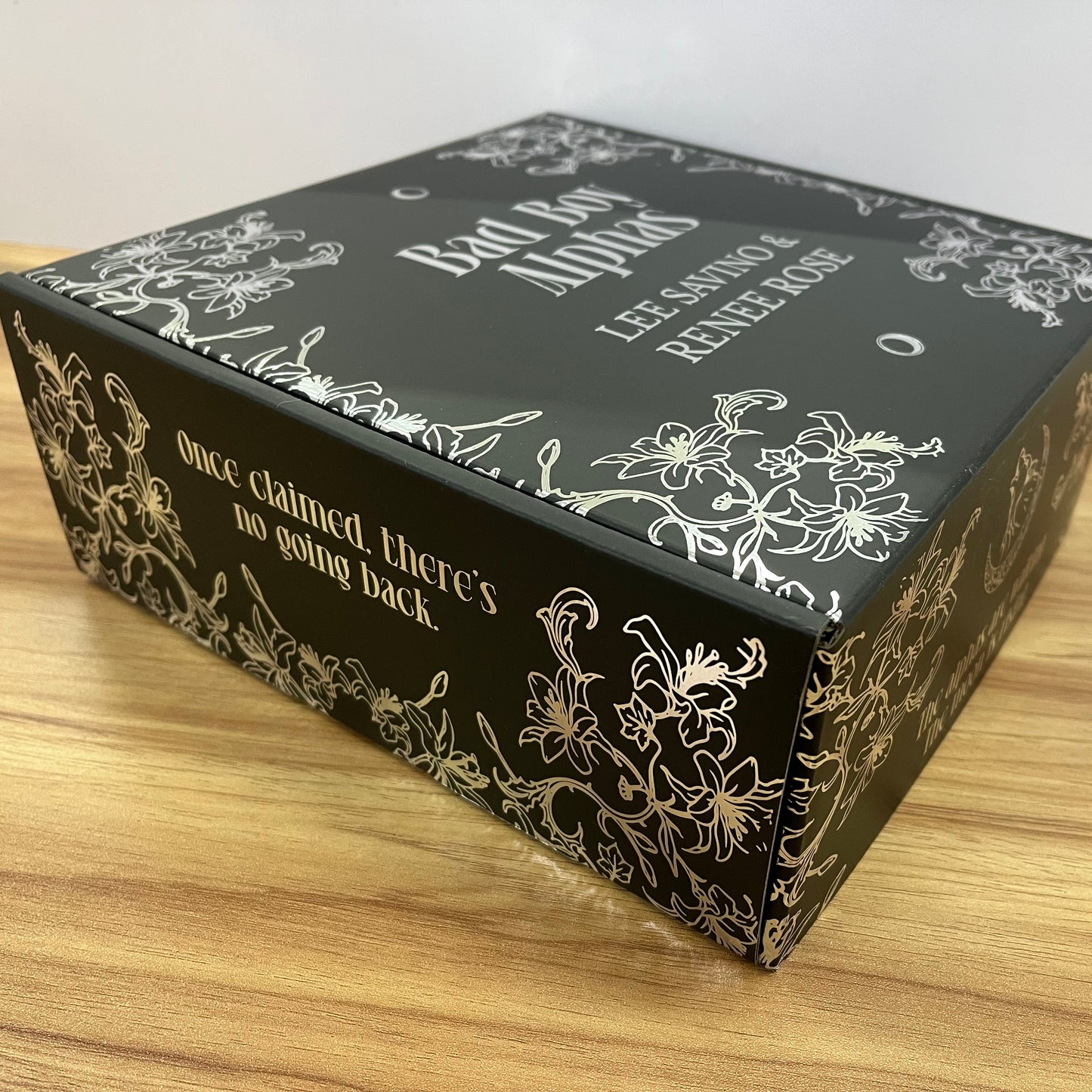 Black box with white text and floral designs on a wooden surface