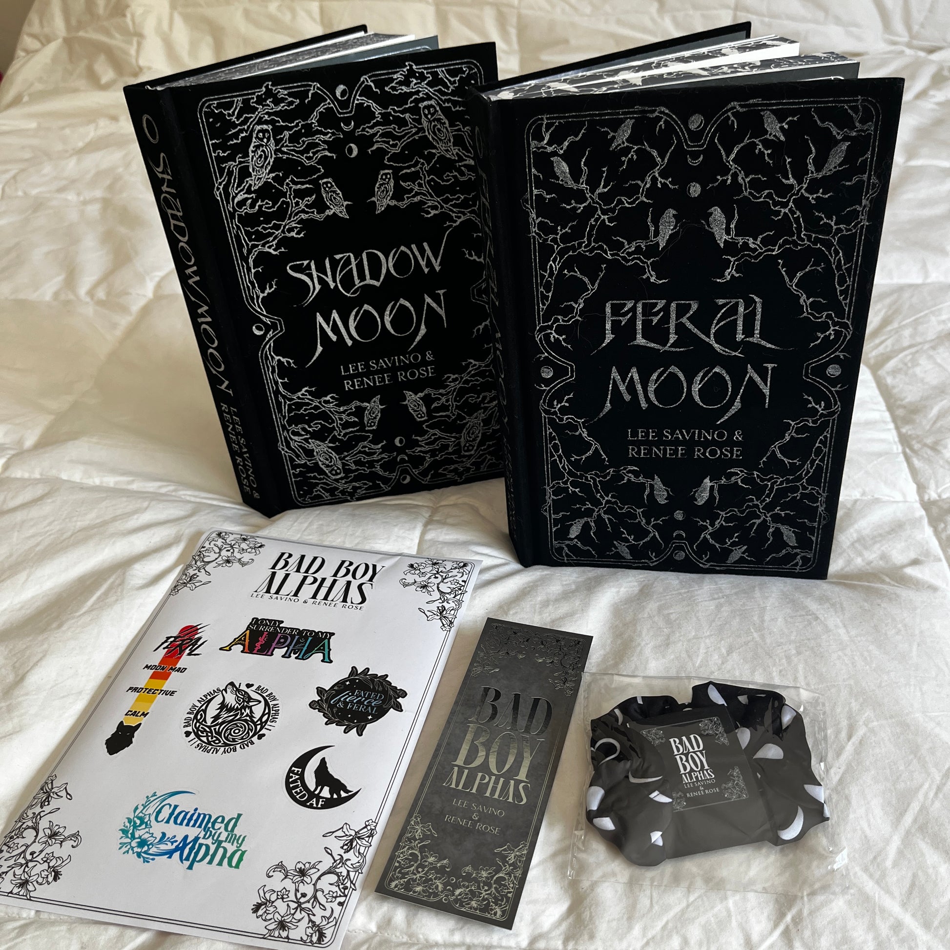 Two books titled 'Shadow Moon' and 'Feral Moon' on a white surface with promotional materials.