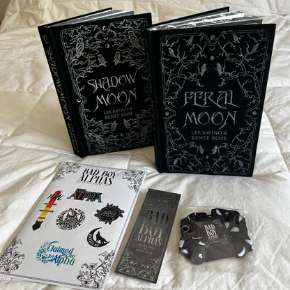 Two books titled 'Shadow Moon' and 'Feral Moon' on a white surface with promotional materials.