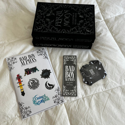 Collection of 'Bad Boy Alphas' merchandise including a box, cards, and stickers on a textured surface.