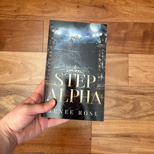 A white person's hand holding a paperback. The cover features a metal car gat. In the background is the night sky and a full moon. In yellow text is the title "Step Alpha." On the bottom in white text is "Renee Rose"