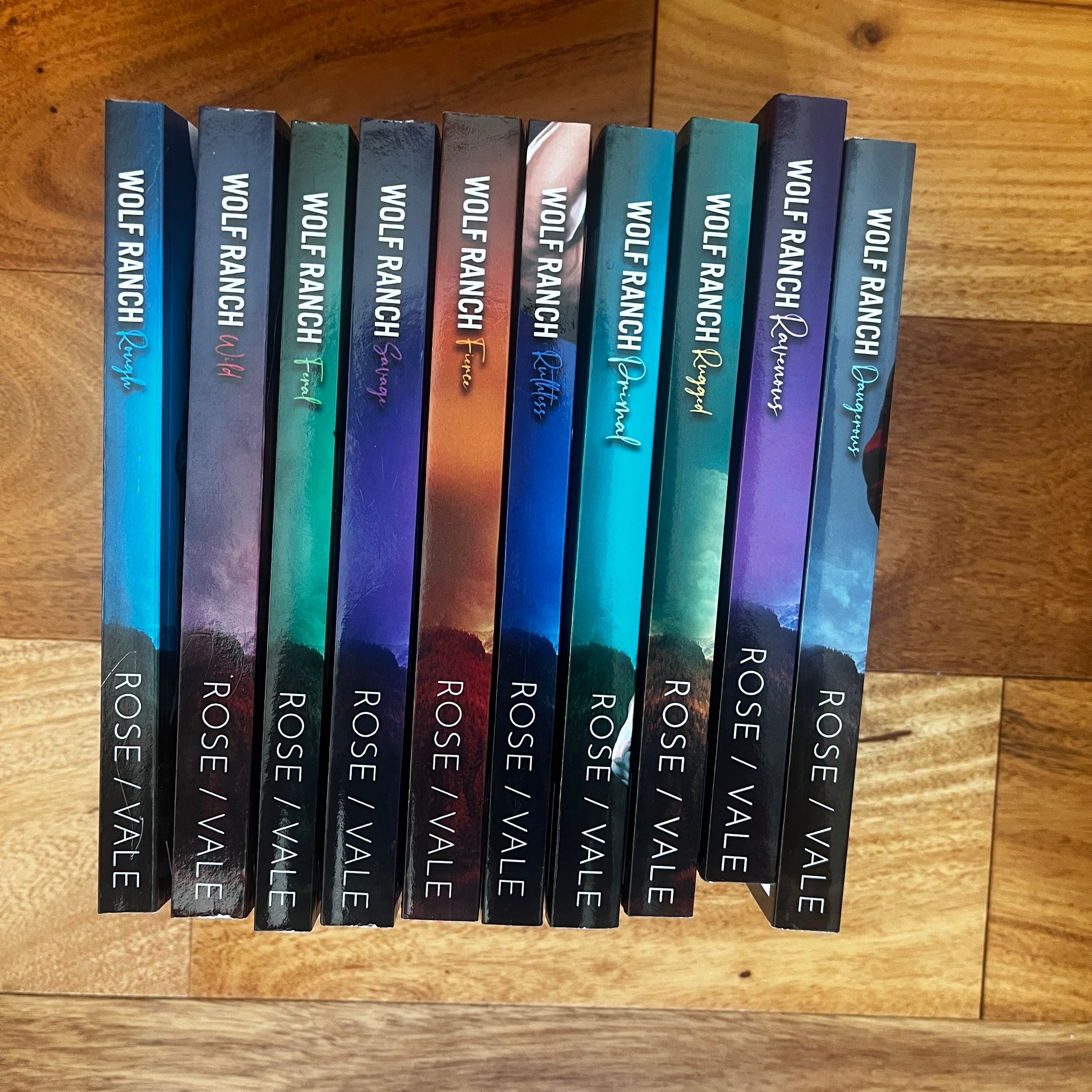 Row of books with visible author and title on wooden surface