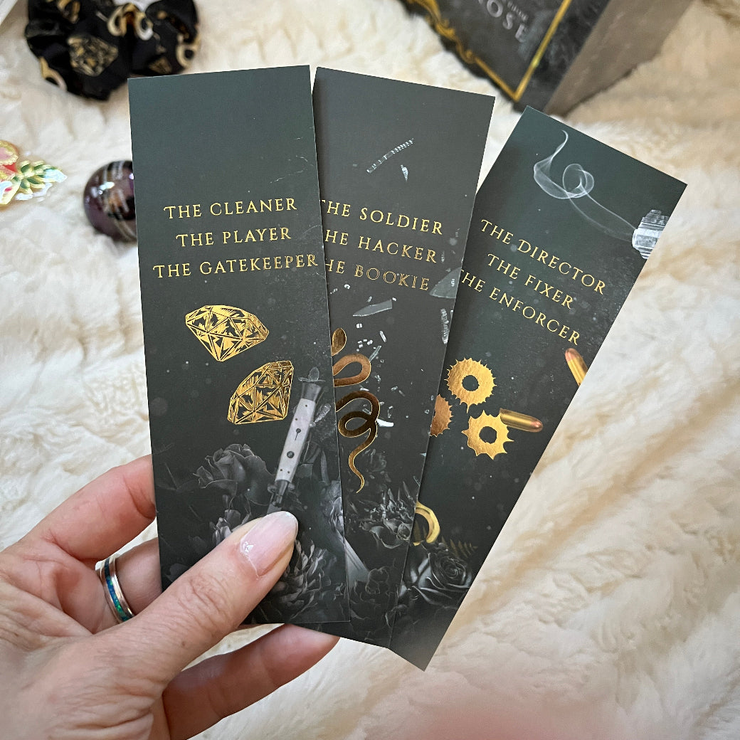Set of black bookmarks back side with gold text and designs on a white textured surface.