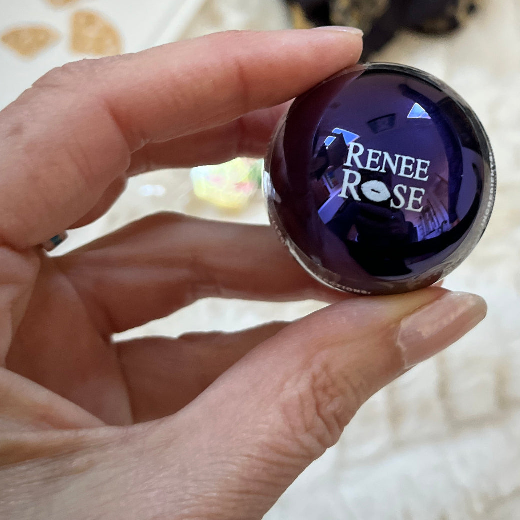 Hand holding a round, lip balm with 'Renee Rose' engraved on it.