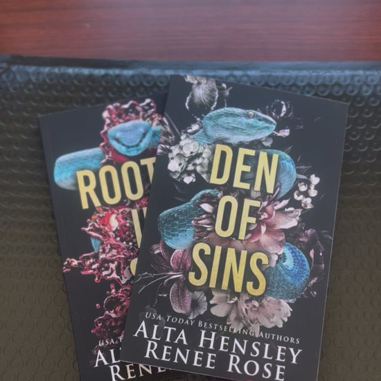 Sped up video. The two books in the Chicago Sin series are fanned out. A white woman -- Renee Rose -- takes the first book "Den of Sins" puts an "Autographed Copy" sticker on it, then draws a big heart, writes "Love and flavors," and signs her name. 