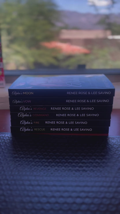 Sped up video. It starts by showing all the books in the Shifter Ops series stacked up. A white woman -- Renee Rose-- takes the top book, puts on a "Autographed Copy" sticker, puts in a sticker, card, and bookmark. In purple, she draws a heart and writes "Love and a fake boyfriend," signs her name and then adds a sticker with Lee Savino's autograph. 