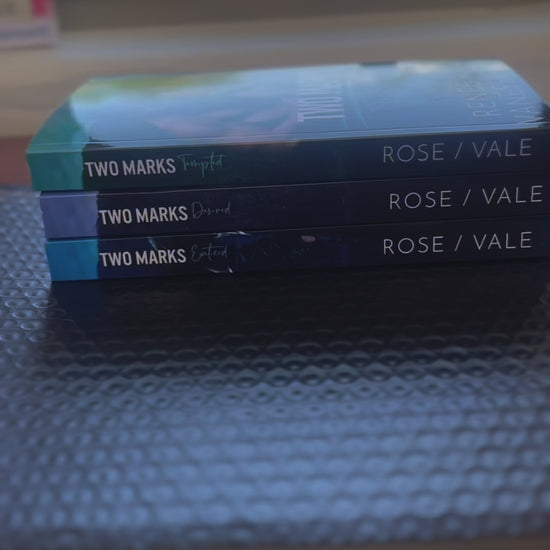 Sped up video. It starts by showing all the books from the Two Marks series in a stack. A white woman -- Renee Rose -- took the top book and signs "Double-wolf love, Renee Rose" ands a sticker of Vanessa Vale's autograph. 