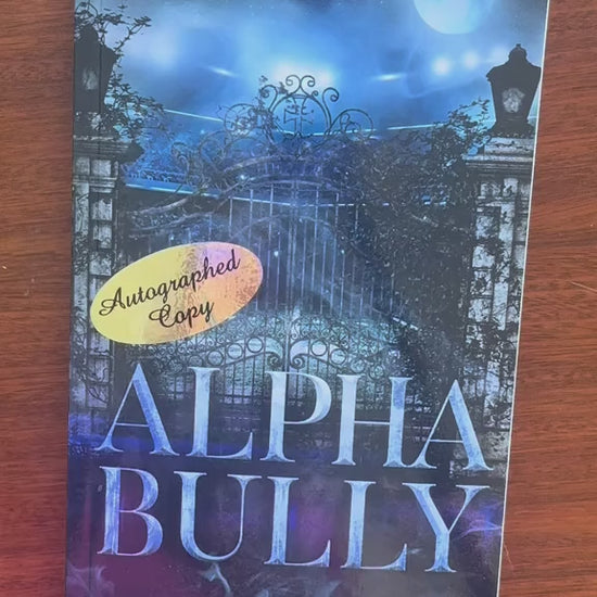 Video of a white woman -- Renee Rose -- opening the "Alpha Bully" book and writing "Love and the (wolf)boy" then signing the paperback. She then puts in some stickers into the book. 