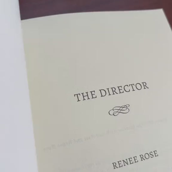 Video of a white woman -- Renee Rose -- drawing a heart, writing the note "Love and a mafia boss," and signs her name in "The Director" paperback. 