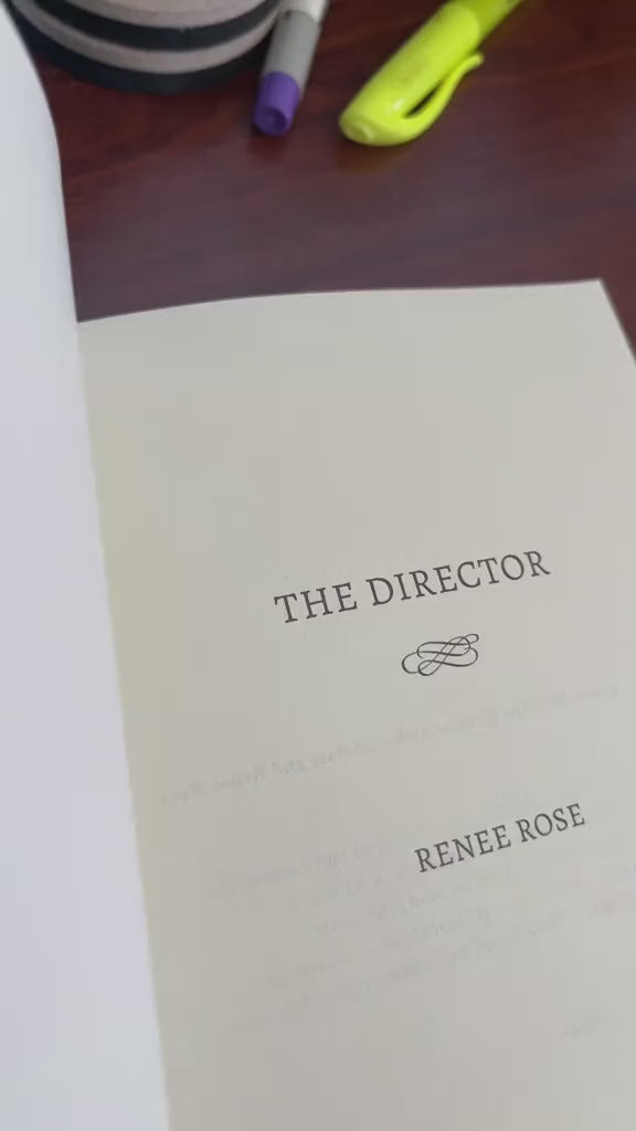 Video of a white woman -- Renee Rose -- drawing a heart, writing the note "Love and a mafia boss," and signs her name in "The Director" paperback. 