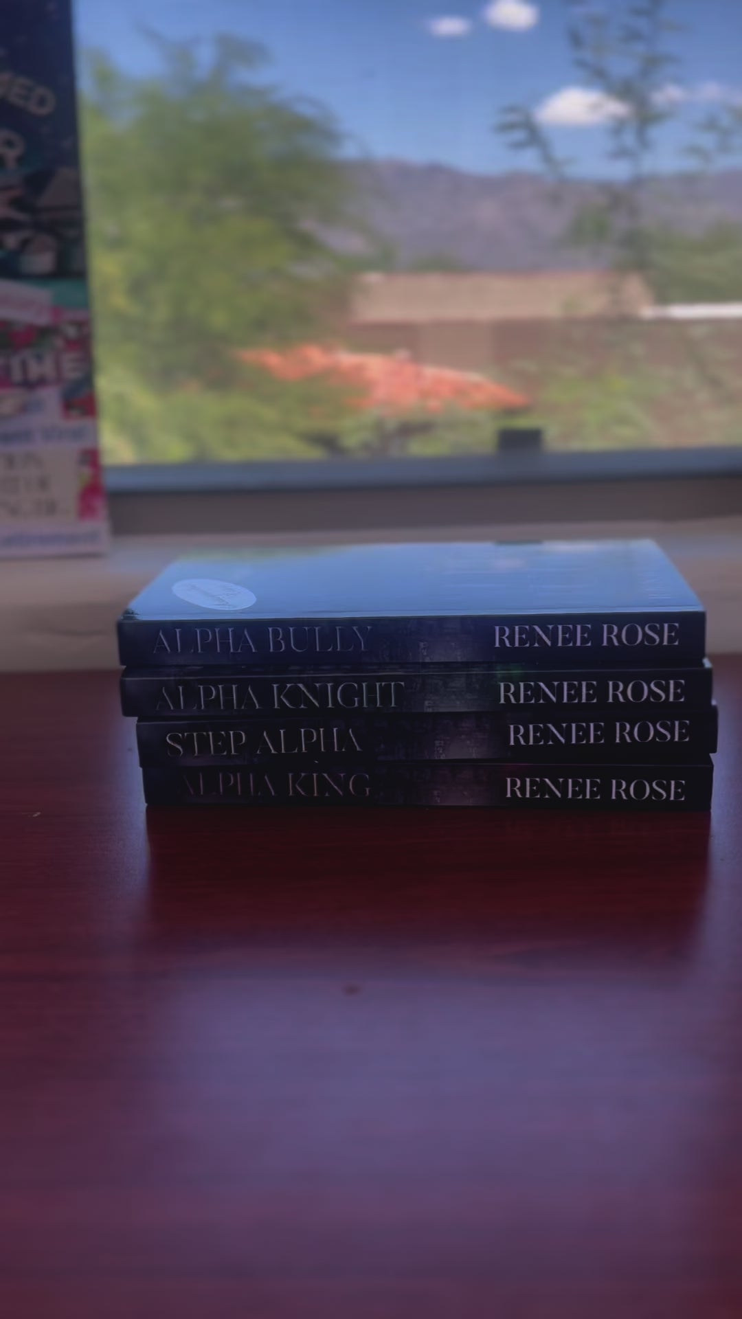 Sped up video. The books from the Wolf Ridge High series are stacked. A white woman -- Renee Rose -- takes the top book with an "Autographed Copy" sticker. She signs it "Love and (wolf) boy next door, Renee Rose"