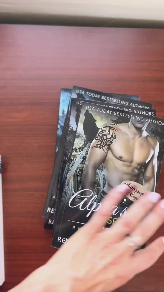 Video of a white woman -- Renee Rose-- writing notes and signing several of the paperbacks from the Bad Boy Alphas Series. 